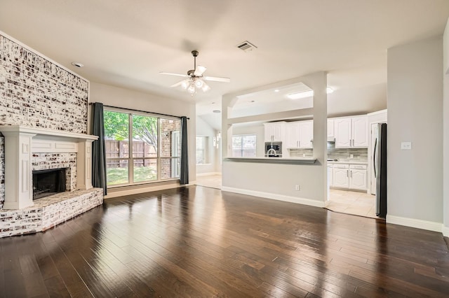 unfurnished living room featuring baseboards, a fireplace, a ceiling fan, and hardwood / wood-style floors