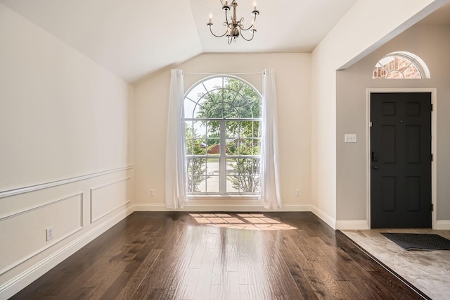 entrance foyer featuring an inviting chandelier, baseboards, vaulted ceiling, and dark wood-style floors