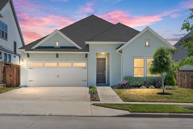 view of front of property with an attached garage, roof with shingles, concrete driveway, and fence