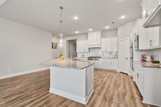 kitchen with tasteful backsplash, light wood-type flooring, appliances with stainless steel finishes, and white cabinets