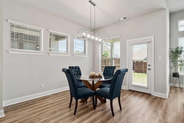 dining space featuring light wood-style flooring, an inviting chandelier, baseboards, and visible vents