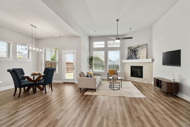 living room featuring a tile fireplace, visible vents, baseboards, and wood finished floors