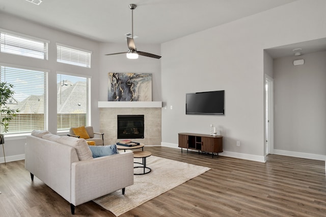 living room with baseboards, ceiling fan, wood finished floors, and a fireplace