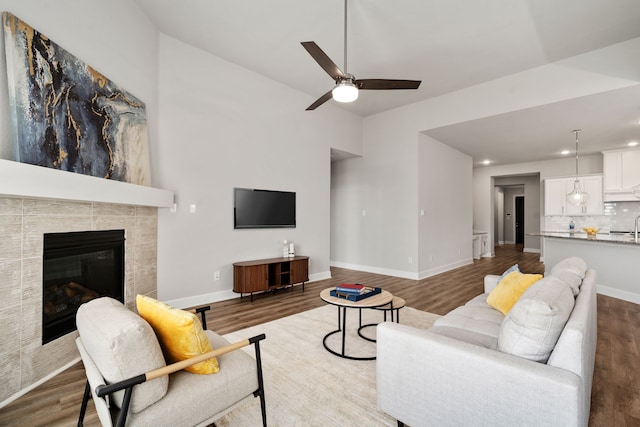 living room with baseboards, recessed lighting, a ceiling fan, lofted ceiling, and wood finished floors