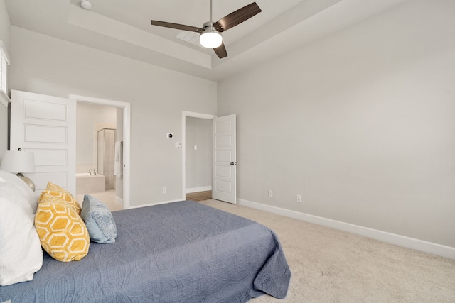 bedroom featuring connected bathroom, a towering ceiling, carpet floors, a raised ceiling, and baseboards