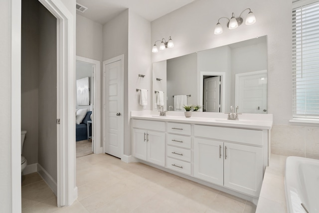 bathroom with visible vents, toilet, a sink, a relaxing tiled tub, and double vanity