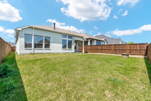 back of house with a yard, a fenced backyard, and brick siding