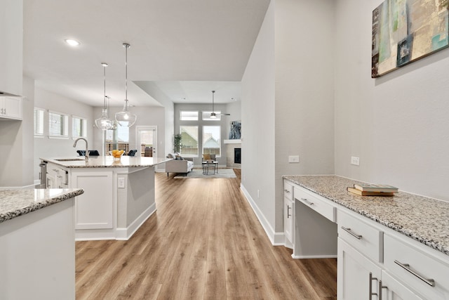 kitchen with a sink, light wood-style flooring, and white cabinets