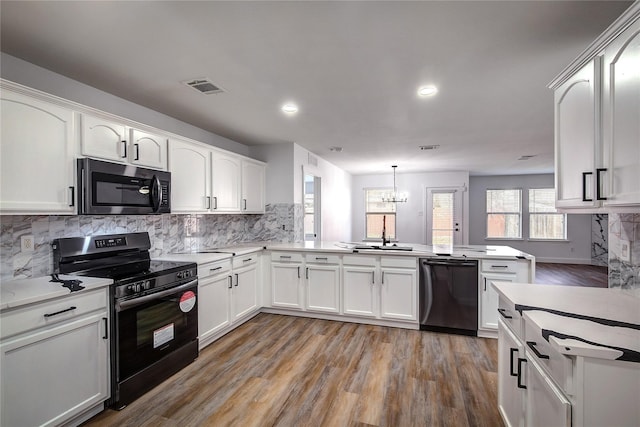 2023 Lake Trail Dr, Heartland, TX 75126 - kitchen with visible vents, a notable chandelier, light wood-type flooring, a peninsula, and black appliances
