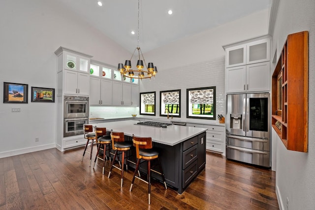 kitchen featuring light countertops, dark wood-style floors, a chandelier, a breakfast bar, and stainless steel appliances