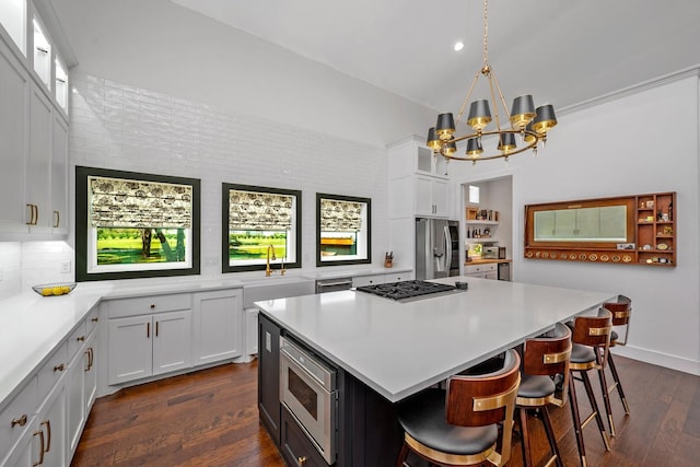 kitchen with a sink, light countertops, white cabinets, a notable chandelier, and stainless steel appliances