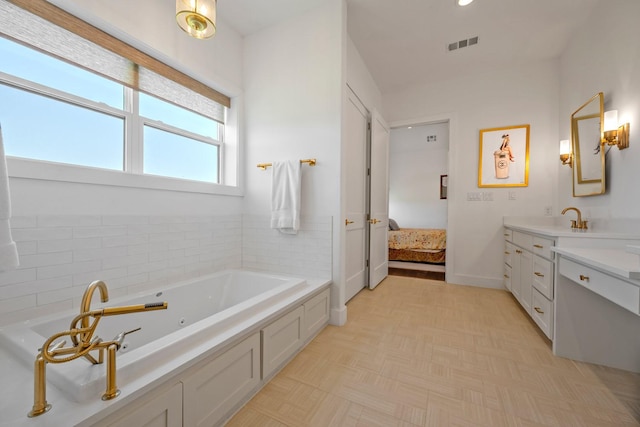bathroom with a garden tub, visible vents, vanity, baseboards, and ensuite bath