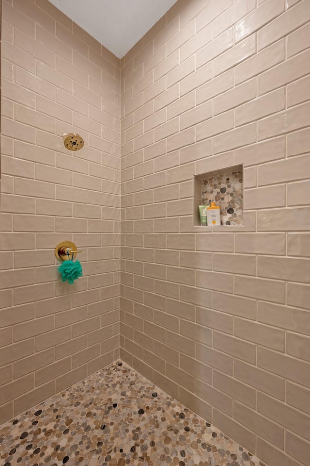 full bathroom with stone finish floor and tiled shower