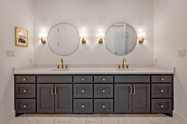 bathroom with double vanity, baseboards, a sink, and marble finish floor