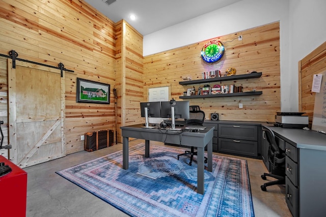 office space with wooden walls, a barn door, concrete floors, a towering ceiling, and visible vents