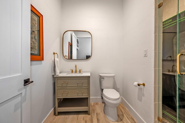 full bathroom with vanity, toilet, baseboards, a shower stall, and wood finished floors