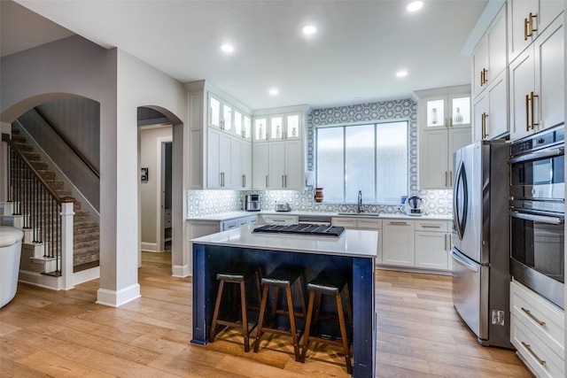 1638 Sandia Ln, Frisco, TX 75033 - kitchen with appliances with stainless steel finishes, a breakfast bar, light countertops, backsplash, and white cabinetry