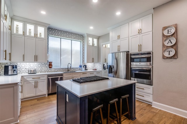 1638 Sandia Ln, Frisco, TX 75033 - kitchen featuring stainless steel appliances, light wood-type flooring, decorative backsplash, a center island, and light countertops
