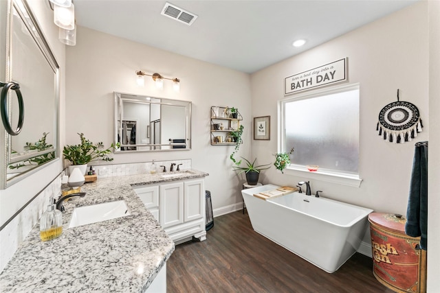7423 Morning Glory Rd, Abilene, TX 79602 - bathroom with wood finished floors, double vanity, a soaking tub, baseboards, and recessed lighting
