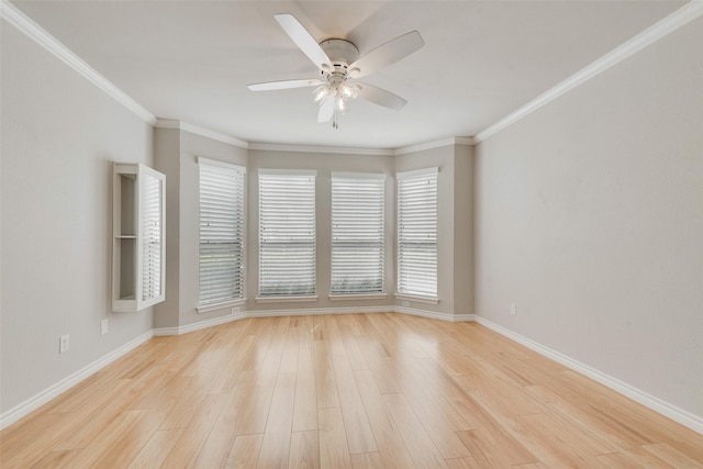 spare room featuring ceiling fan, plenty of natural light, light wood-style flooring, baseboards, and ornamental molding