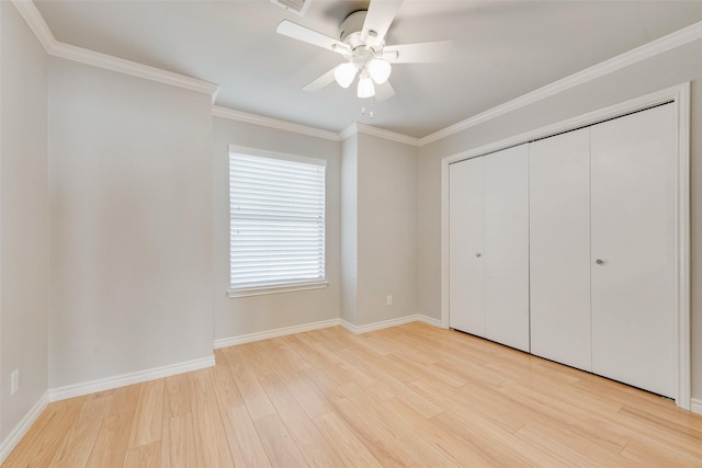 unfurnished bedroom with wood finished floors, ornamental molding, baseboards, a closet, and a ceiling fan