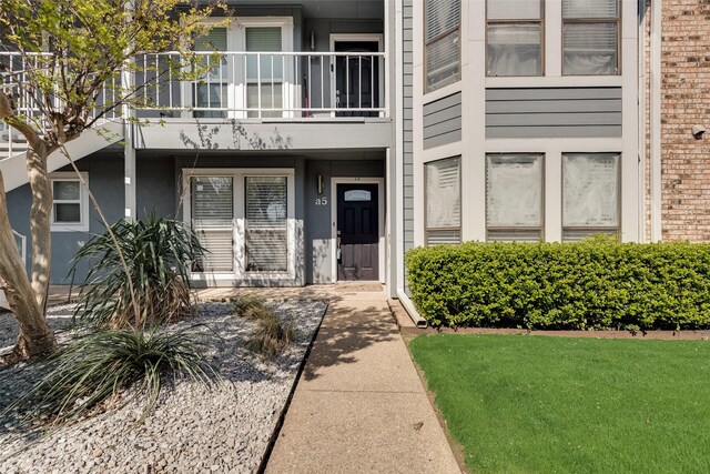 view of exterior entry featuring a balcony and stucco siding