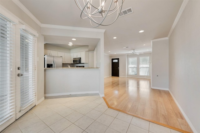 kitchen with stainless steel appliances, white cabinets, ornamental molding, light tile patterned floors, and baseboards