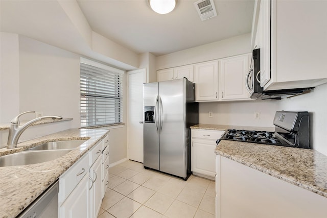 kitchen featuring stainless steel appliances, a sink, light tile patterned floors, white cabinets, and light stone countertops