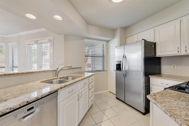 kitchen featuring appliances with stainless steel finishes, a sink, light tile patterned floors, white cabinetry, and ornamental molding