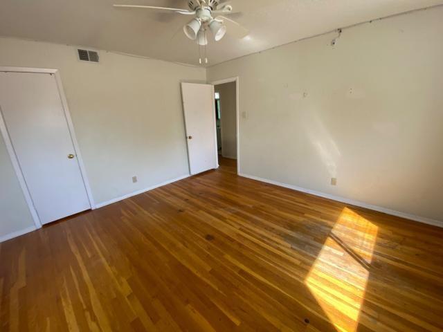 4219 Parkwood Dr, San Antonio, TX 78218 - unfurnished bedroom featuring wood finished floors, ceiling fan, baseboards, and visible vents