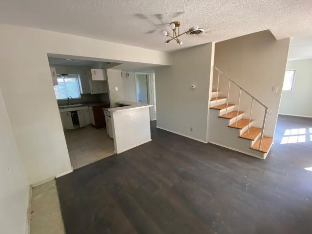 4219 Parkwood Dr, San Antonio, TX 78218 - unfurnished living room with a textured ceiling, a sink, plenty of natural light, and stairs