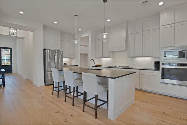 263 Observation Dr N, Aledo, TX 76008 - kitchen featuring stainless steel appliances, a sink, dark countertops, light wood-style flooring, and an island with sink