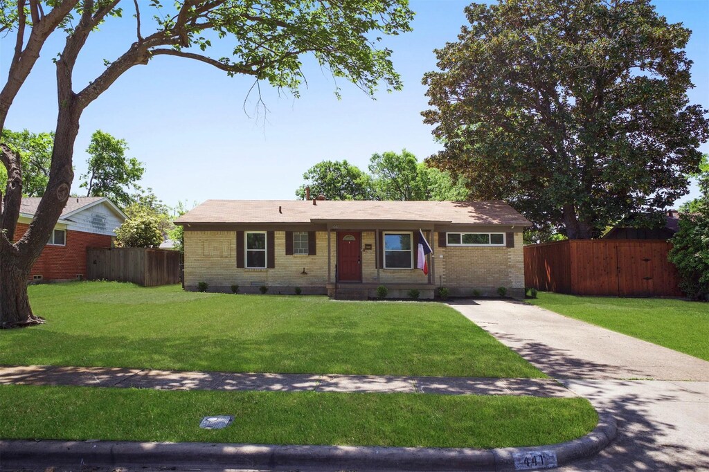 ranch-style home featuring concrete driveway, fence, a front lawn, and brick siding