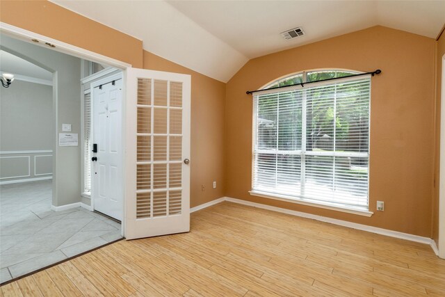 empty room featuring visible vents, vaulted ceiling, and wood finished floors