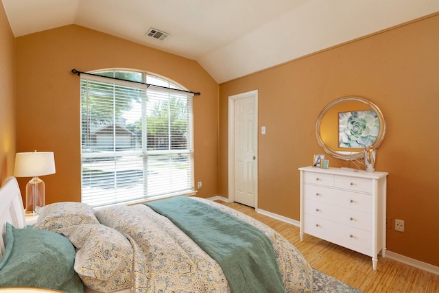 bedroom with visible vents, baseboards, vaulted ceiling, and light wood-style flooring