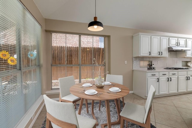 dining room with light tile patterned floors, baseboards, and vaulted ceiling
