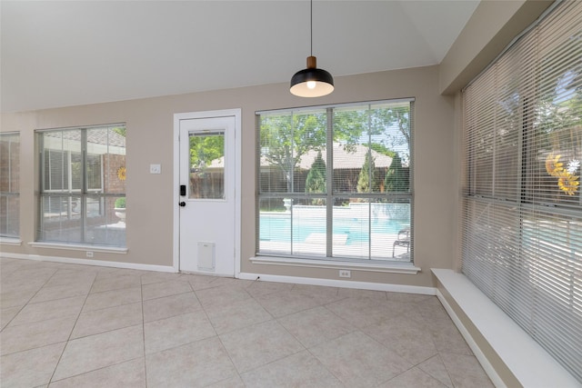 unfurnished dining area with light tile patterned floors, baseboards, lofted ceiling, and plenty of natural light