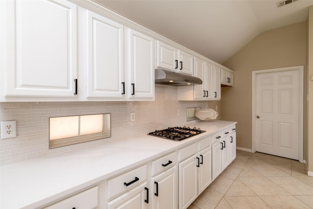 kitchen with white cabinets, stainless steel gas cooktop, under cabinet range hood, lofted ceiling, and decorative backsplash