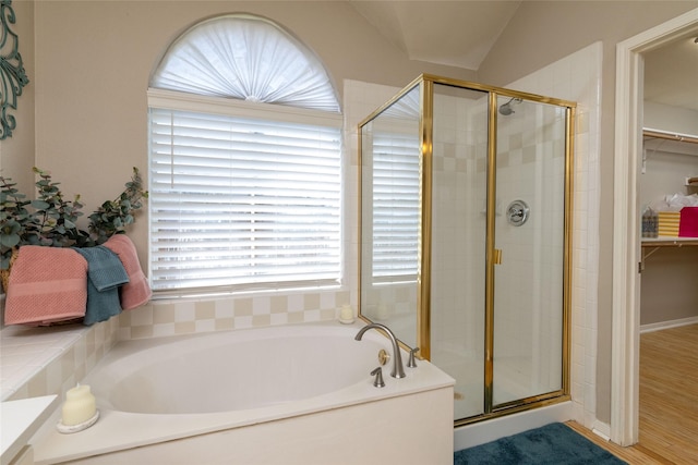 full bathroom with a shower stall, a spacious closet, and a bath
