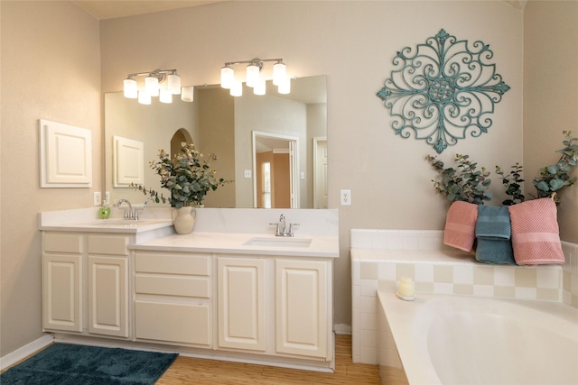 bathroom featuring a bathing tub, wood finished floors, double vanity, and a sink