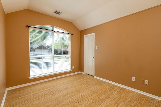 unfurnished room with visible vents, baseboards, light wood finished floors, and vaulted ceiling