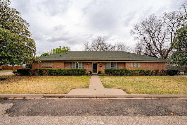 ranch-style house featuring fence, a front lawn, and brick siding