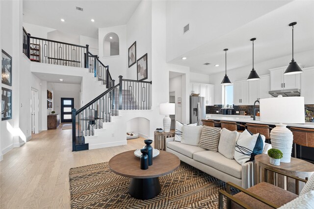 2913 Spring Valley Way, Anna, TX 75409 - living area with light wood-type flooring, a towering ceiling, visible vents, stairs, and baseboards