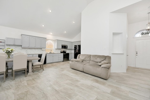living area with high vaulted ceiling, a notable chandelier, and recessed lighting