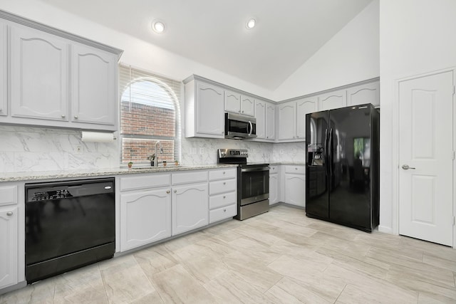kitchen with a sink, black appliances, light stone countertops, decorative backsplash, and lofted ceiling