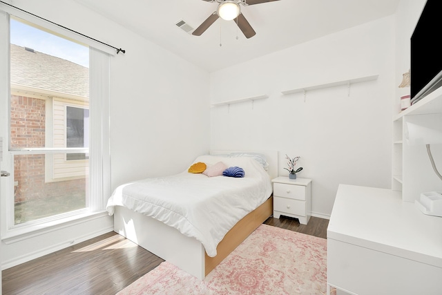 bedroom featuring visible vents, multiple windows, baseboards, and wood finished floors
