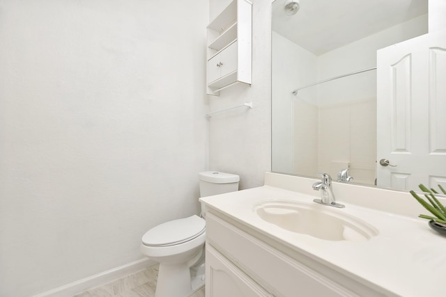 bathroom with toilet, vanity, and baseboards