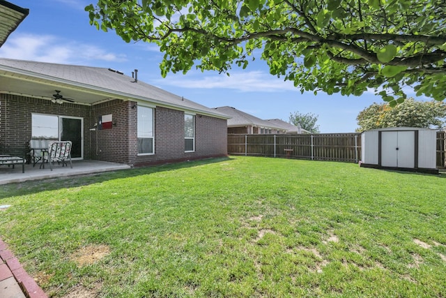 view of yard featuring a storage shed, a ceiling fan, a fenced backyard, an outdoor structure, and a patio