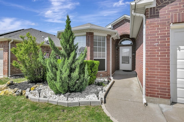 property entrance with brick siding and an attached garage