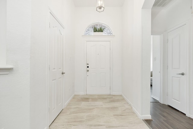 entrance foyer featuring visible vents, baseboards, and arched walkways